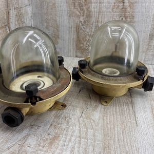 Könnte beinhalten: Zwei Vintage-Deckenleuchten im Industriestil aus Messing und Glas mit klaren Glasschirmen und schwarzen Akzenten.