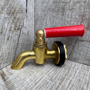 May include: A brass faucet with a red handle. The faucet has a round spout and a threaded connection. The handle is made of plastic and has a smooth surface.