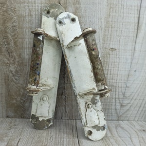 Könnte beinhalten: Zwei antike weiße Türklinken mit einem gesprenkelten braunen und weißen Rollenknauf. Die Griffe sind aus Metall und haben einen abgegriffenen Look.