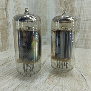 May include: Two clear glass vacuum tubes with metal caps and pins. The tubes are filled with a dark liquid and have a metallic sheen.