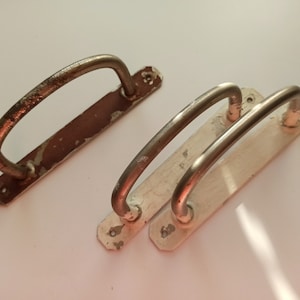 May include: Two antique door handles with metal loops and a white and brown painted base.