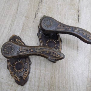 May include: Two antique door handles with ornate designs. The handles are made of metal and have a dark brown finish. The handles are in good condition and would be a great addition to any home.