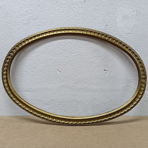 Puede incluir: Marco de fotos ovalado de color dorado antiguo. El marco tiene un patrón detallado y repetitivo a lo largo de los bordes interior y exterior. El marco está vacío, sin imagen ni respaldo. El marco está hecho de un material dorado.