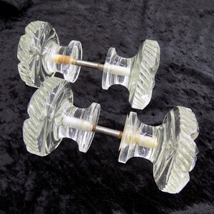 Peut inclure: Deux paires de boutons de porte en verre transparent avec un motif en spirale décoratif. Les boutons sont fixés à des tiges métalliques.