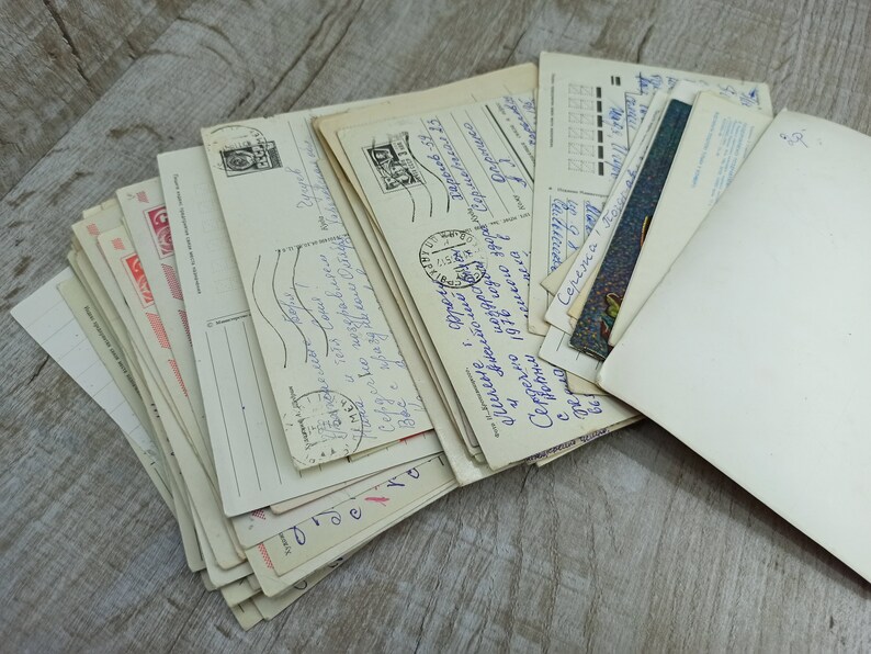 May include: A collection of vintage postcards, featuring handwritten messages, stamps, and postmarks. The postcards are in various sizes and orientations, with a mix of colors and designs. Some cards have text in a foreign language.