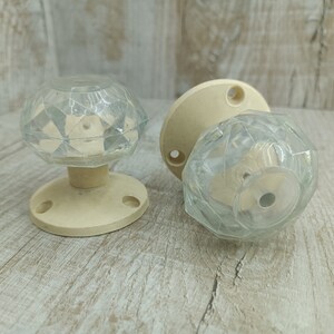 May include: Two vintage door knobs with clear glass diamond-shaped handles and off-white plastic bases.