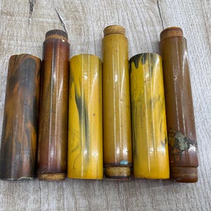 May include: Six vintage brown and yellow patterned plastic tubes with a wood-like texture.