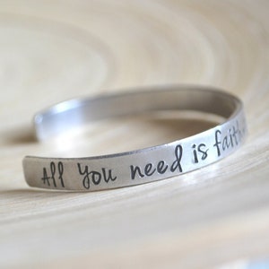 May include: A silver metal bracelet inscribed with the words "All you need is faith".