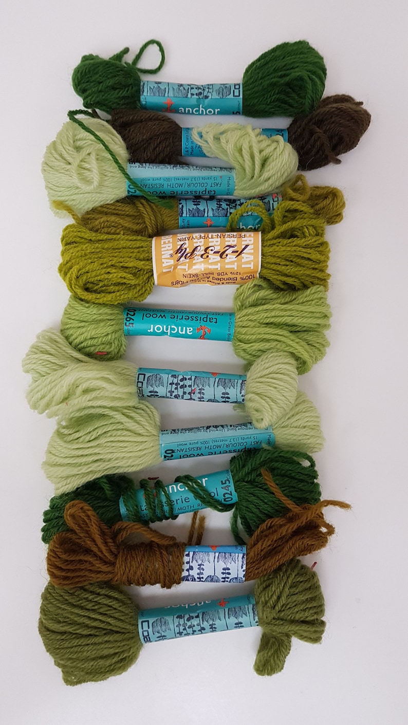Pode incluir: Uma cole&ccedil;&atilde;o de 10 novelos de l&atilde; Anchor Tapisserie em v&aacute;rios tons de verde. Os r&oacute;tulos nos novelos dizem "Anchor Tapisserie Wool" e "Persian-Type Yarn".