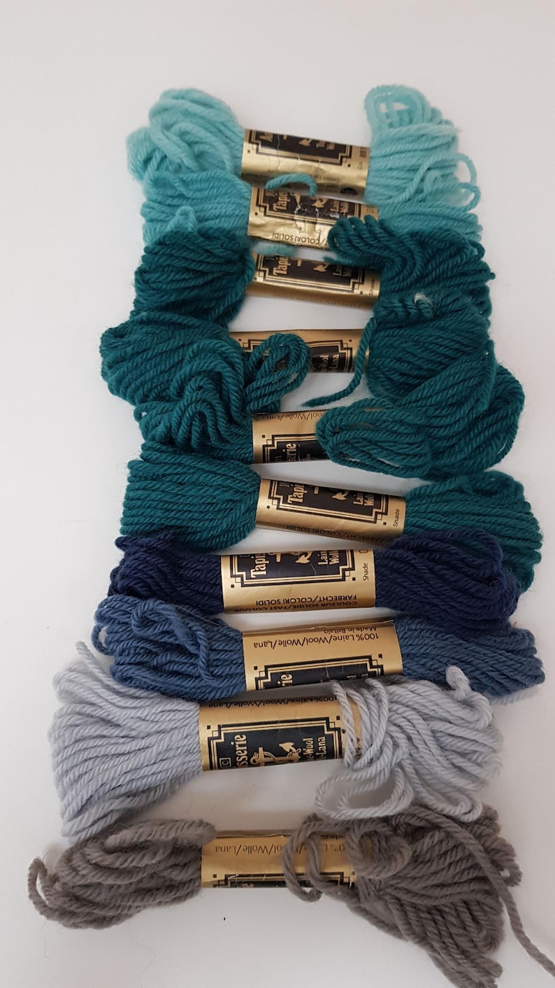 Pode incluir: Conjunto de 10 novelos de fio para bordar em tons de azul, verde e cinza. O fio &eacute; enrolado em carret&eacute;is de cart&atilde;o com etiquetas douradas que dizem "Tapisserie" e "100% Laine/Wool/Wolle/Lana".