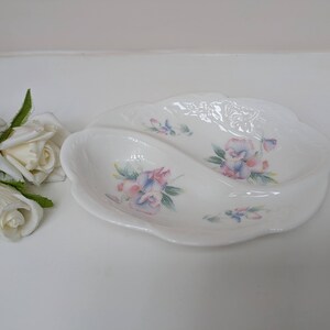 May include: A white ceramic serving dish with a divided section. The dish is decorated with a floral pattern of pink, purple, and blue flowers.