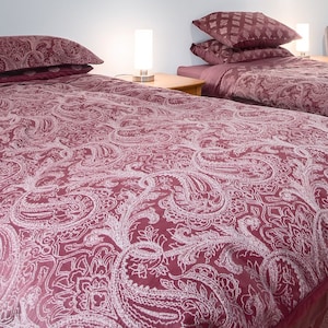 May include: Two twin-sized beds with red paisley patterned bedding and white pillows. The beds have matching red bed skirts.