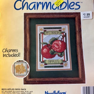 May include: A cross stitch kit featuring a red apple design with the text "Mecarron Apples" in a brown wooden frame. The kit includes DMC floss, needle, thread palette, complete directions and stitch instructions. The kit is from Needleform and is printed in the USA.