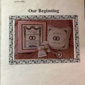 May include: A cross-stitch pattern booklet titled "Our Beginning" with a pink and white striped background. The cover features a cross-stitch design of a wedding arch with the text "And this our life our beginning" and "Jon and Steve October 8, 1989".