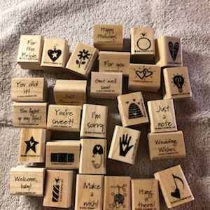 May include: A collection of 24 wooden rubber stamps with various designs and phrases, including "You're Sweet!" and "Just a Note".