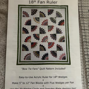 May include: A white instructional sheet for the Stack-n-Whack 18 degree Fan Ruler, featuring a Bow Tie Fans quilt pattern with colorful fan-shaped blocks, text details for 5 inch to 12 inch blocks, and a partial view of a clear acrylic ruler.