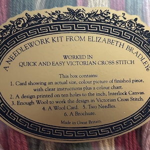 May include: An oval gold label for a needlework kit from Elizabeth Bradley, featuring a black decorative border with floral motifs and Greek key patterns. The text details the contents, including interlock canvas, wool, needles, and instructions.