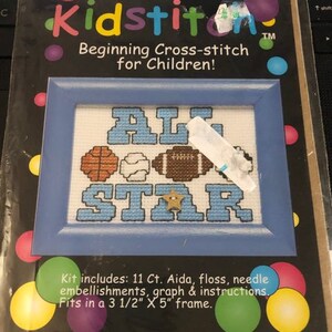May include: A Mini Kidstitch cross-stitch kit for children. The kit features a blue framed design with the words "ALL STAR" in blue cross-stitch. Includes a basketball, baseball, and football. The kit fits a 3.5" x 5" frame.
