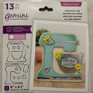 May include: A Gemini Create-a-Card papercraft die set featuring a mixer design. The set includes 13 pieces, with the largest die measuring 6" x 6.1". The card design includes the text "You are a cupcake in a world full of muffins."
