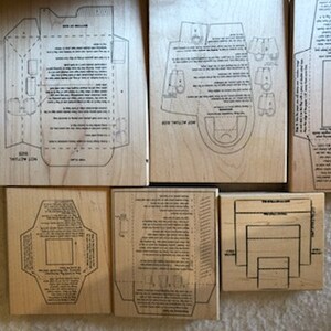 May include: Set of nine wooden stamps for crafting, featuring various envelope and card designs. The stamps are made of natural wood and have a light brown color.