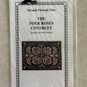 May include: A cross-stitch pattern titled "The Four Roses Coverlet" by Nancy Sturgeon. The design features four rose motifs in tan on a black background, framed by a decorative border. The pattern is packaged in a clear plastic sleeve.