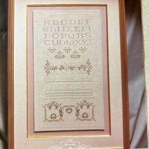 May include: Cross stitch pattern for a sampler with the alphabet, a floral design, and the text "The Love Sampler". The pattern is from Cross 'N Patch and is number 70.