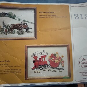 May include: A package containing two framed embroidery kits. One depicts an old wagon in a landscape, the other a red flower train. The finished sizes are 12" x 14" and 12" x 16". The Creative Circle brand is visible.