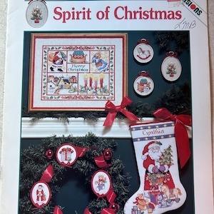 May include: A cross-stitch pattern booklet featuring a Christmas stocking with a Santa Claus design, a wreath with ornaments, and a framed cross-stitch design with a winter scene. The title of the pattern is "Spirit of Christmas" by Susan Winget.