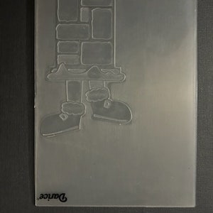 May include: Clear plastic craft die featuring a Santa Claus leg and foot with a brick chimney in the background. The die is labeled "Darice" in the bottom left corner.