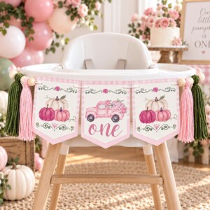 May include: A high chair banner featuring three pennants with pink and white gingham borders. The outer pennants display watercolor pumpkins, while the center pennant shows a pink truck with flowers and the word one. Includes green tassels.