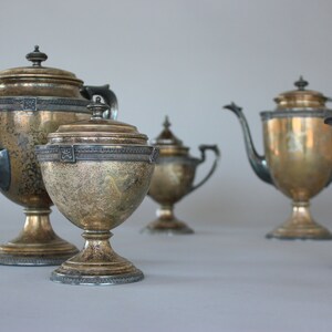 Puede incluir: Un juego de té de plata con una tetera, jarra de crema, azucarero y una tetera más grande. El juego de té tiene un diseño ornamentado y está en excelente estado.