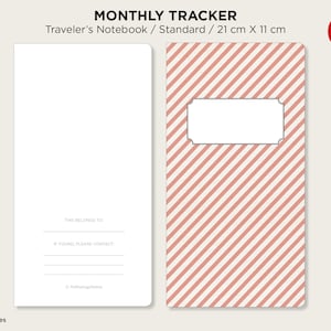 May include: A pink and white striped notebook cover with a blank label. The cover is for a standard size traveler's notebook, measuring 21 cm by 11 cm. The text "MONTHLY TRACKER" is printed at the top of the cover.