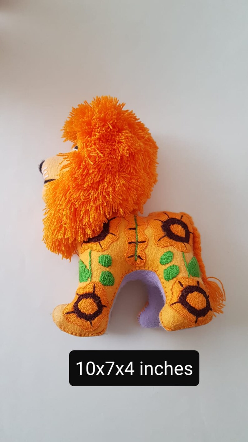 Puede incluir: Le&oacute;n de fieltro naranja y amarillo con girasoles bordados. El le&oacute;n mide 25,4 cm de largo, 17,8 cm de alto y 10,2 cm de ancho.