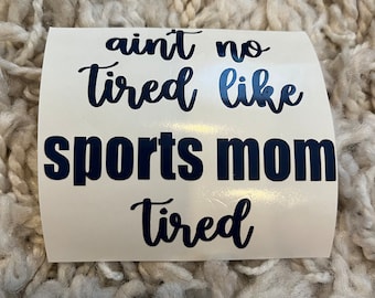 May include: A white sticker with black text that reads "ain't no tired like sports mom tired".