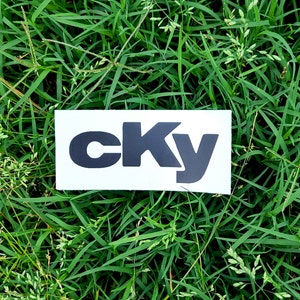 May include: A white sticker with the word "CKY" printed in black bold letters.