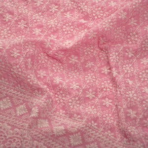 May include: Pink fabric with white embroidered floral pattern. The fabric is soft and delicate, with a subtle sheen.