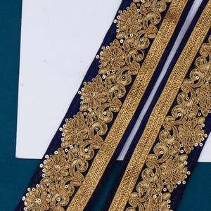 May include: Two strips of navy blue trim with gold embroidery and sequins. The trim features a floral design.