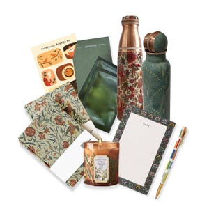 May include: A gift set featuring a variety of items, including a candle, two copper water bottles, a notepad, a pen, and two sets of patterned fabric napkins. The candle is brown with a floral design and the text "Sandalwood Vanilla". The water bottles are copper with floral and geometric patterns. The notepad has a green and white floral border and the text "Notes". The pen is multi-colored and the napkins are green and white with a floral pattern. The set is perfect for a housewarming gift or a special occasion.