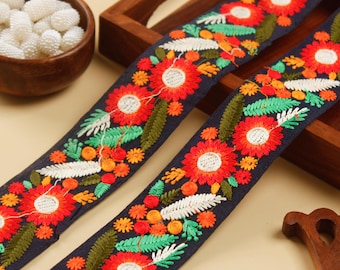 Könnte beinhalten: Zwei Stücke marineblauer Besatz mit bunten, gestickten Blumenmustern. Der Besatz zeigt rote, orange, gelbe, grüne und weiße Blumen und Blätter.