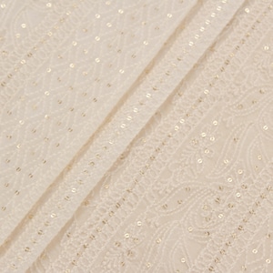 May include: Close-up of a white fabric with a delicate gold pattern. The fabric has a subtle sheen and a soft texture.