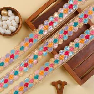 May include: Three rows of colorful, scalloped trim with sequins and embroidery. The trim is a mix of pink, purple, orange, turquoise, and gold.
