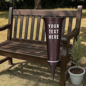 May include: A dark brown, cone-shaped garden planter with a white band near the bottom and the text "YOUR TEXT HERE" in white. The planter is placed on a brown wooden bench next to a small potted evergreen.