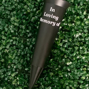 May include: Black plastic flower vase with a pointed base for inserting into the ground. The vase has the text "In Loving Memory of" printed on the side.