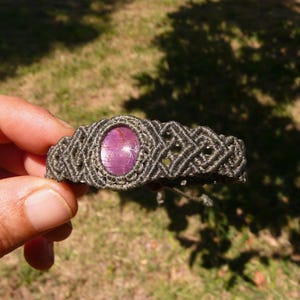 Bracciale a manetta intrecciato a mano in Macramè filato color grigio-verde con pietra naturale Rubino Stella vista lato destro primo piano su sfondo natura.