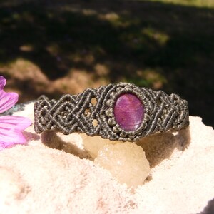 Bracciale a manetta intrecciato a mano in Macramè filato color grigio-verde con pietra naturale Rubino Stella vista lato destro esposto su minerale grezzo.