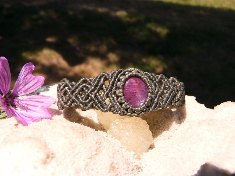 Bracciale a manetta intrecciato a mano in Macramè filato color grigio-verde con pietra naturale Rubino Stella vista lato destro esposto su minerale grezzo.