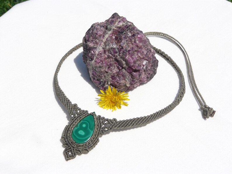 Collana girocollo realizzata a mano in tecnica Macramè da Rasikoserena con pietra naturale verde Malachite naturale, di forma a goccia e taglio cabochon.
Gioiello esoterico di colore grigio/verde anallergico e regolabile in misura grazie alla chiusura scorrevole in legno. Pezzi unici artigianali comodi da indossare, inclusi di confezione regalo.