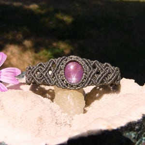 Bracciale a manetta intrecciato a mano in Macramè filato color grigio-verde con pietra naturale Rubino Stella vista centrale esposto su minerale grezzo.