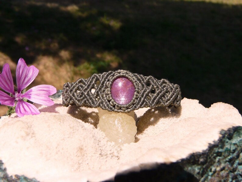 Bracciale a manetta intrecciato a mano in Macramè filato color grigio-verde con pietra naturale Rubino Stella vista centrale esposto su minerale grezzo.