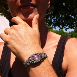 Bracciale a manetta intrecciato a mano in Macramè filato color grigio-verde con pietra naturale Rubino Stella, primo piano indossato da ragazza con canotta nera.